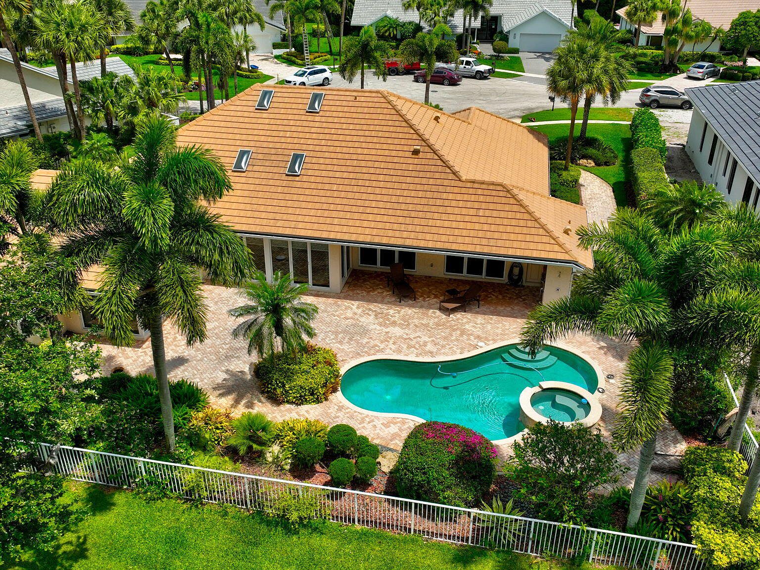 Aerial view of 4960 Cherry Laurel Lane, a one-story Delaire Country Club residence with a curved private pool and spa wrapped by mature palms, opening onto the championship golf course